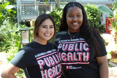 Two students smiling and wearing matching Richard M. Fairbanks School of Public Health tee shirts.